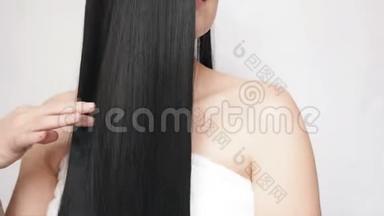 年轻女孩抚摸着长长的头发，表现出她们的光<strong>滑</strong>和<strong>丝滑</strong>。 漂亮的女士关心头发