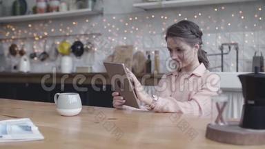 年轻女子坐在家里的餐桌旁，用一台数码平板电脑做她的<strong>小生</strong>意。 库存数据