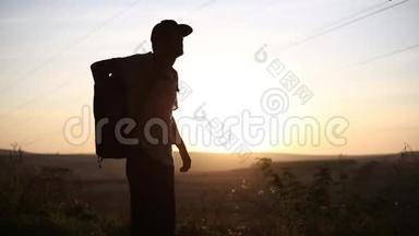 日落时带背包的徒步旅行者剪影，用钢<strong>制热</strong>水瓶饮水。