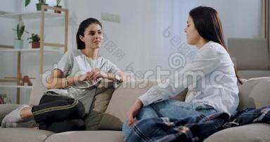 两个女朋友在沙发的客厅里微笑着聊天，非常友好，他们在一起度过了美好的时光
