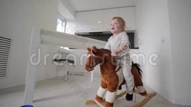 <strong>孩子</strong>的<strong>成长</strong>，可爱可爱的小男孩骑着毛绒马，在家里的房间里微笑