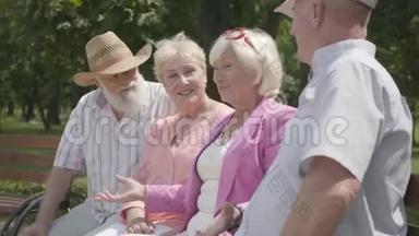 两对可爱的成熟夫妇在<strong>夏天</strong>公园里坐在长凳上聊天和微笑。 老年夫妇双人<strong>约会</strong>