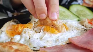 女人吃传统的英式<strong>早餐</strong>，有<strong>煎鸡蛋</strong>、烤面包、火腿和培根。 特写