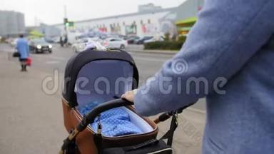 妈妈手里拿着婴儿车手柄，推着婴儿车。 母亲和婴儿一起在婴儿车里散步