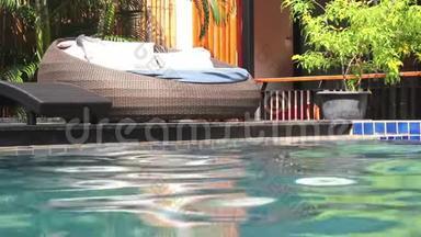 在阳光明媚的日子里，游泳池和<strong>休闲椅</strong>上有水波纹和枕头。