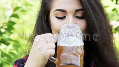年轻快乐的美丽女人的肖像，她从玻璃中<strong>喝</strong>啤酒，<strong>解渴</strong>，微笑，看镜头