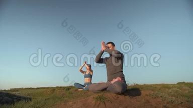 瑜伽疗法，运<strong>动男女</strong>在蓝天背景下一起在山顶上的莲花位置冥想