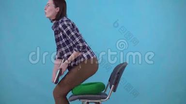 女人坐在蓝色背景的椅子上的矫形枕头上，痔疮的概念