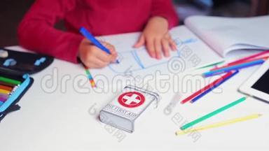 一个儿童急救箱躺在学校一个男孩旁边的桌子上
