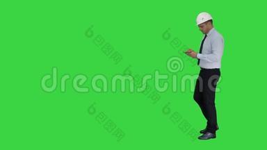 戴着头盔和正式衣服的男人四处<strong>走动</strong>，在绿色屏幕上做笔记，铬键。