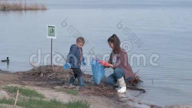 环保，小男孩帮助母亲志愿者清理污染的河堤塑料垃圾和