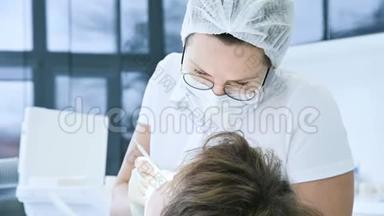 女<strong>牙医</strong>戴眼镜面罩和白帽检查病人的口腔。 <strong>牙医</strong>`的工作