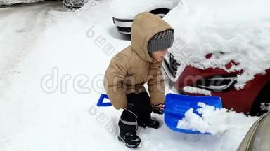3岁的小男孩用铲子在停车场挖雪的4k镜头