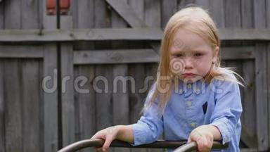 一个留着白色头发和蓝色眼睛的小可爱女孩手里拿着一辆农车
