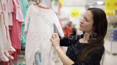 在超市、购物中心、商场里，一个漂亮的女孩为孩子挑选衣服，`孩子们的衣服