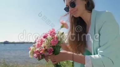 喜笑颜开的花店<strong>小</strong>姑娘戴着墨镜，在<strong>河边</strong>的草地上收集一束束美丽的鲜花
