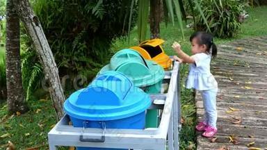 亚洲小女孩把空塑料瓶扔进公园的回收垃圾桶