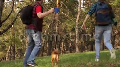 饲养员带着一只狗和一个成年女儿在散步。 一家人和一只狗在树林里旅行。 旅行者爸爸，女儿