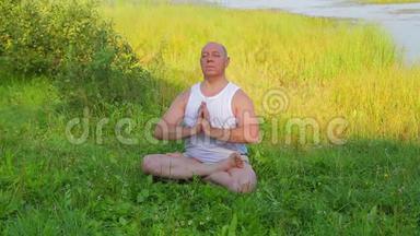 一个中年人早上在湖边做呼吸瑜伽和冥想。