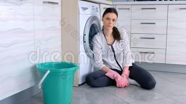 疲惫的女人戴着粉红色的橡胶<strong>手套</strong>在<strong>厨房</strong>地板上清洗后看着相机。