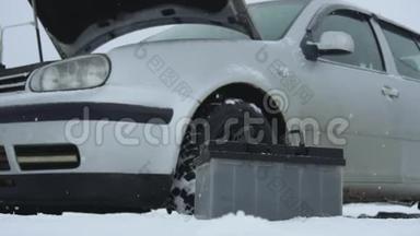 冬季降雪时破车故障或问题.. 汽车电池躺在汽车旁边。 帽子或帽子