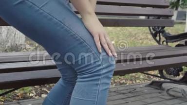 站在长凳上的女人感到公园里膝盖剧痛，骨关节炎，受伤