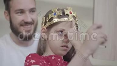 一位漂亮的小胡子父亲把王冠戴在他的小女孩的头上，使她成为公主，而她的公主
