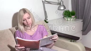 年轻的金发女人坐在沙发上，翻阅着文件夹