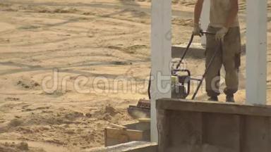 一名男工人在铺设瓷砖的道路<strong>施工</strong>过程<strong>中</strong>夯实沙子。 土壤凝结设备，<strong>建筑</strong>