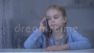 伤心的小女孩在雨天打电话，独自呆在家里，思念母亲