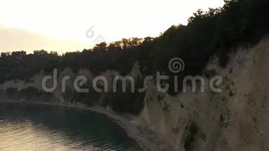 在海岸边沿悬崖飞行的无人机在日落的陆地上上升到高处