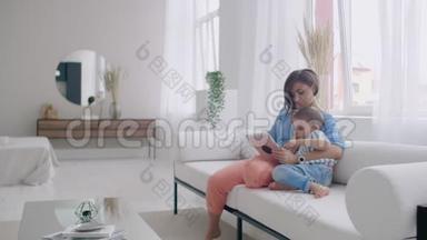 幸福的<strong>家</strong>庭妈妈和孩子儿子坐在沙发上用<strong>数码</strong>平板电脑，微笑的父母和孩子的儿子抱着电脑