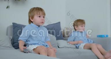 两个男孩，4岁和2岁，坐在沙发上看电视。 令人兴奋的<strong>电视节目</strong>。 观看漫画