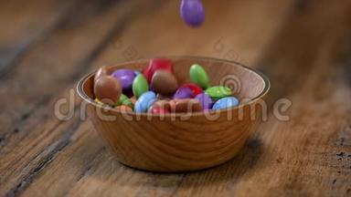 慢动作，五颜六色的<strong>糖果</strong>放在木碗箱中，孤立在木背景上