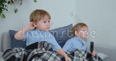 两个男孩，4岁和2岁，坐在沙发上看电视。 令人兴奋的电视节目。 看动画片。 孩子们看着