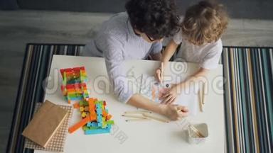 一个年轻的女人和一个孩子一起用铅笔在平板上画画