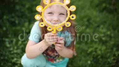 超级可爱的金发小女孩穿着t恤在草地上吹肥皂泡。