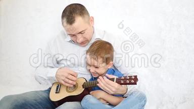 父亲抱着他的小儿子，教他<strong>弹吉他</strong>，开朗的孩子拍拍<strong>吉他</strong>，就像她<strong>弹吉他</strong>一样。