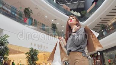 一个带着购物袋在商场里四处张望的快乐女人的低角度镜头