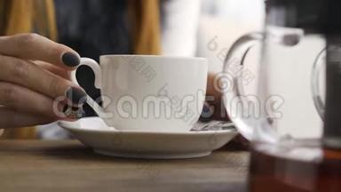 <strong>白种人</strong>女人在咖啡馆里坐着的<strong>时候</strong>，用黑色的指甲触摸着白色的茶杯。 年轻女子放松