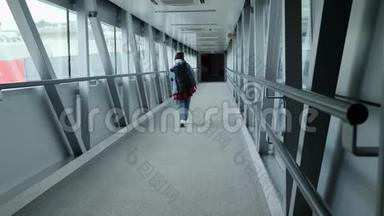 在机场候机楼的门桥上，可以看到登机的女游客的背影。旅游理念