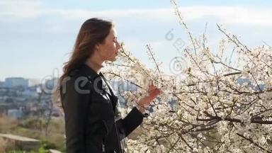 年轻漂亮的姑娘在春天慢动作地嗅着樱桃树的白花