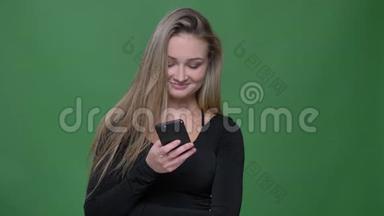 年轻女商人穿着黑色衬衫<strong>看</strong>着智能<strong>手机</strong>，<strong>笑</strong>着<strong>看</strong>绿色背景的肖像。