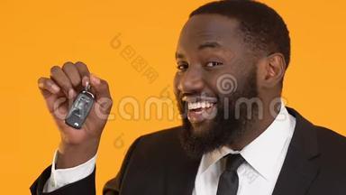 快乐的非裔美国男经理把车钥匙放进相机，租房服务