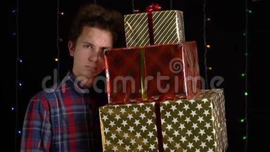 带黑背景礼盒的男孩。 新年快乐、圣诞快乐、情人节`礼品盒