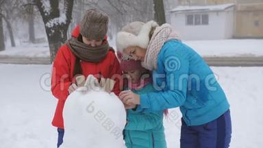 妈妈和两个女儿在冬天装饰鹅卵石一起堆雪人。