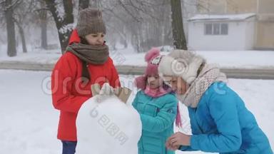 妈妈和两个女儿在冬天装饰鹅卵石一起堆雪人。