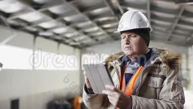 一个戴着安全帽、穿着工作服的人正站在机库的中间，拿着平板电脑对着镜头偷东西