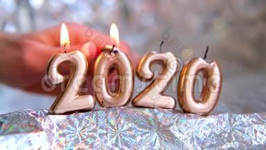 女子手中点亮一盏烛光2020.. 金色的蜡烛在燃烧。 模糊的银色背景。 圣诞快乐，新年快乐