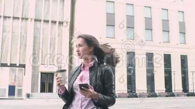 漂亮的商业女孩站在街头背景，看着电话，喝着一杯纸杯里的咖啡。 <strong>强者</strong>